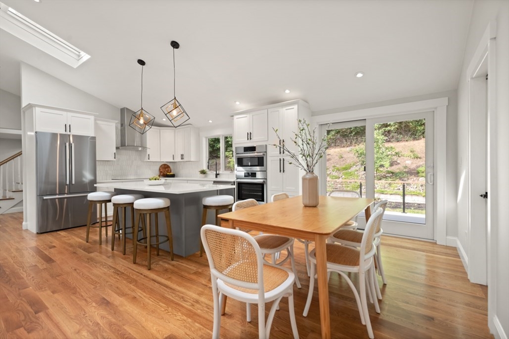 17 Saunders Road Lynnfield, MA 01940 - Photo 15 of 42 a kitchen with stainless steel appliances kitchen island granite countertop a dining table chairs and white cabinets