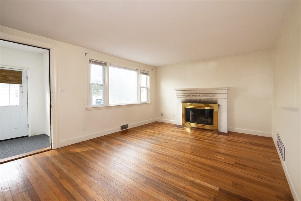 43 E Street Hull, MA 02045 - Photo 3 of 12 an empty room with wooden floor fireplace and windows