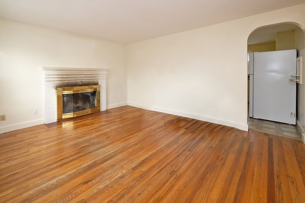 43 E Street Hull, MA 02045 - Photo 4 of 12 an empty room with wooden floor and fireplace