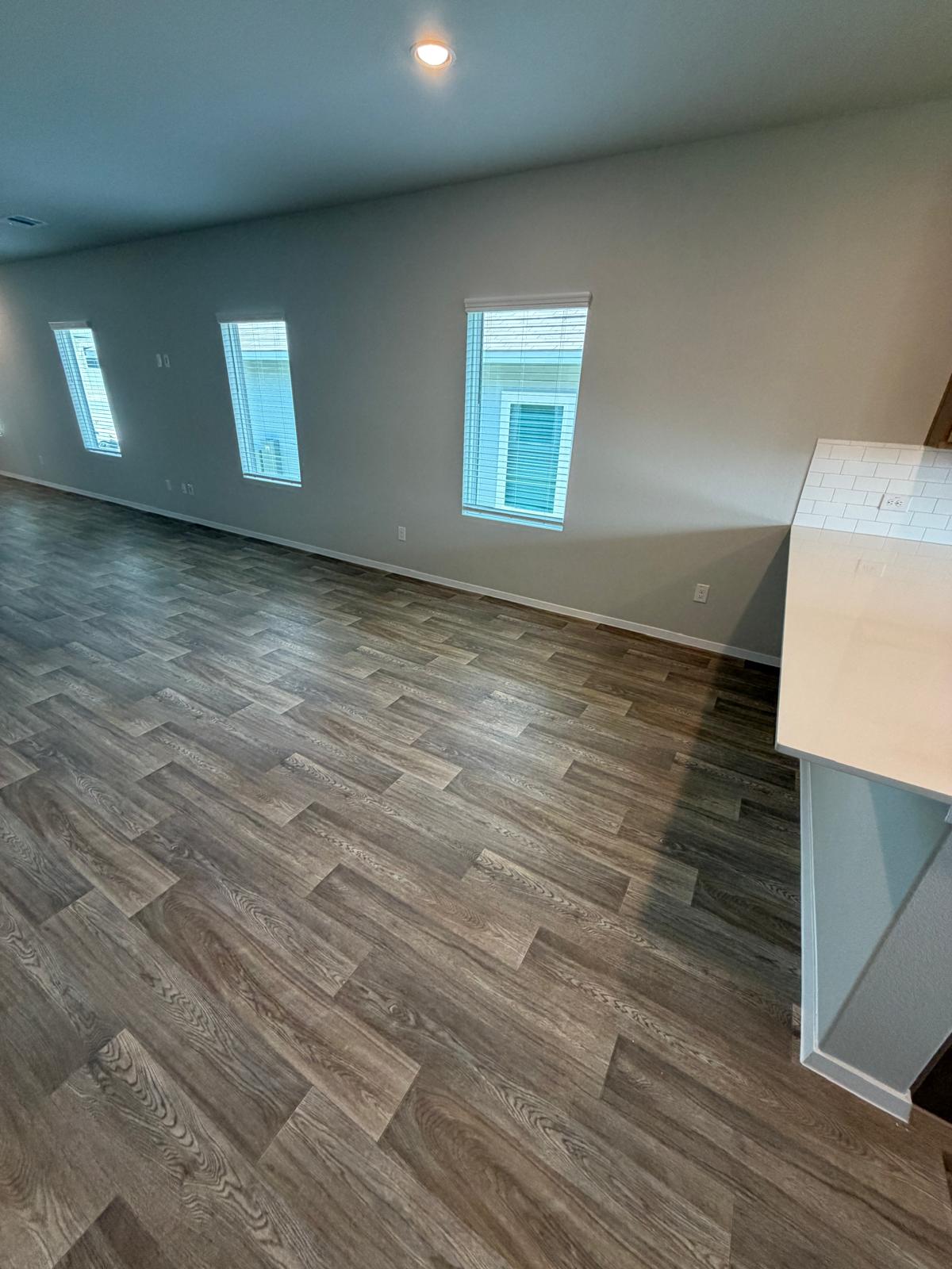 2701 Towy Road Manor, TX 78653 - Photo 9 of 35 Herringbone pattern flooring creates a visual anchor in this naturally illuminated space, perfect for entertaining.