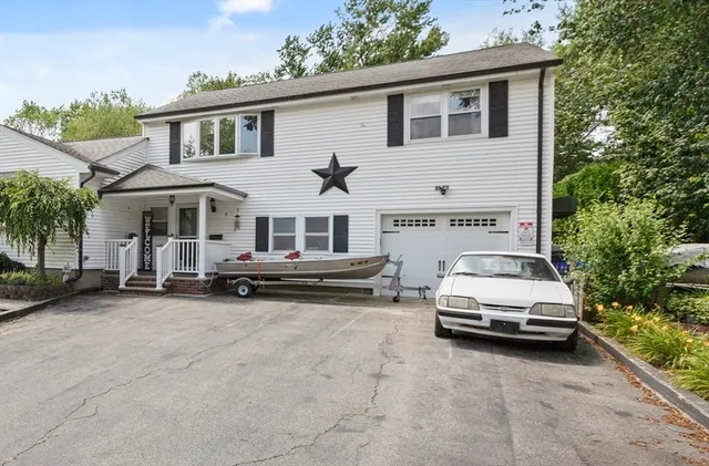 a view of a white house and a yard with a car parked in front of it