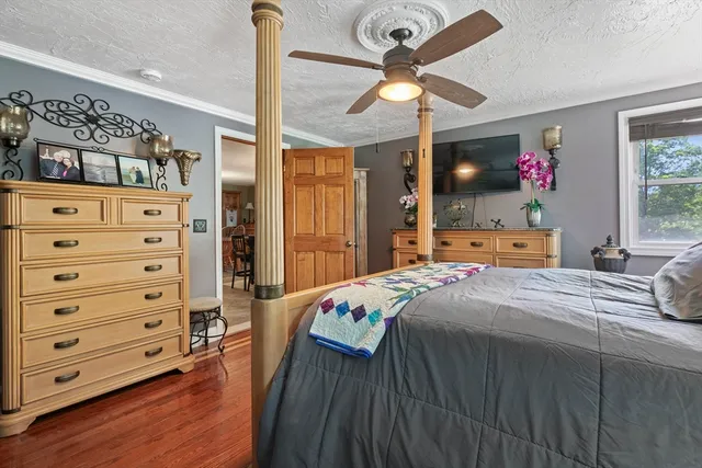 a bedroom with a bed a dresser and potted plants