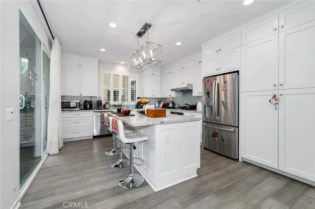 a kitchen with stainless steel appliances a refrigerator a stove a sink dishwasher and a refrigerator with wooden floor