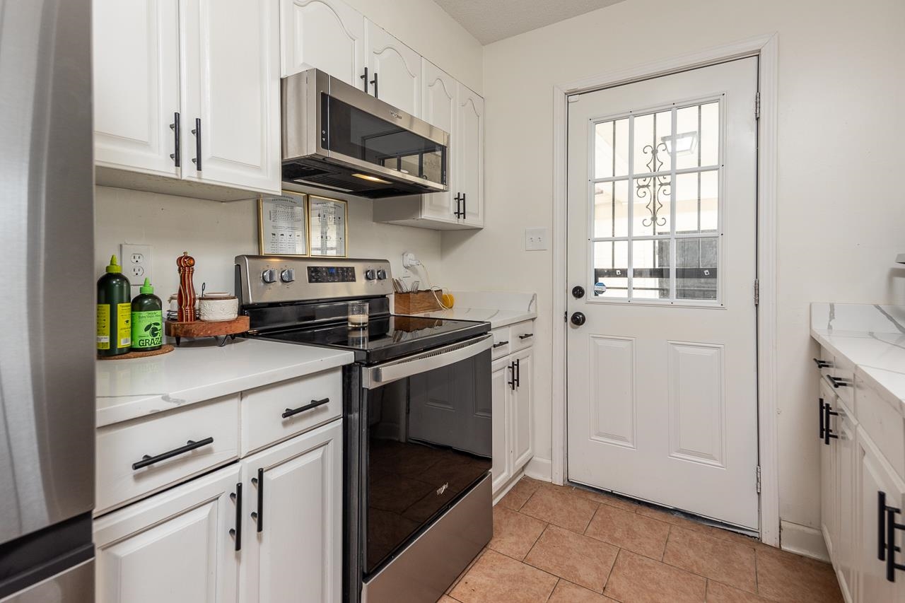 2835 McVay Trail Drive Memphis, TN 38119 - Photo 14 of 29 Kitchen featuring light stone counters, light tile patterned floors, white cabinets, and stainless steel appliances