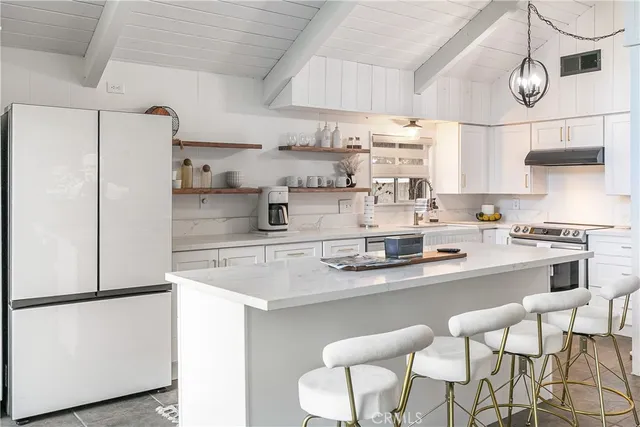 a kitchen with stainless steel appliances granite countertop a sink a stove a refrigerator and white cabinets with wooden floor