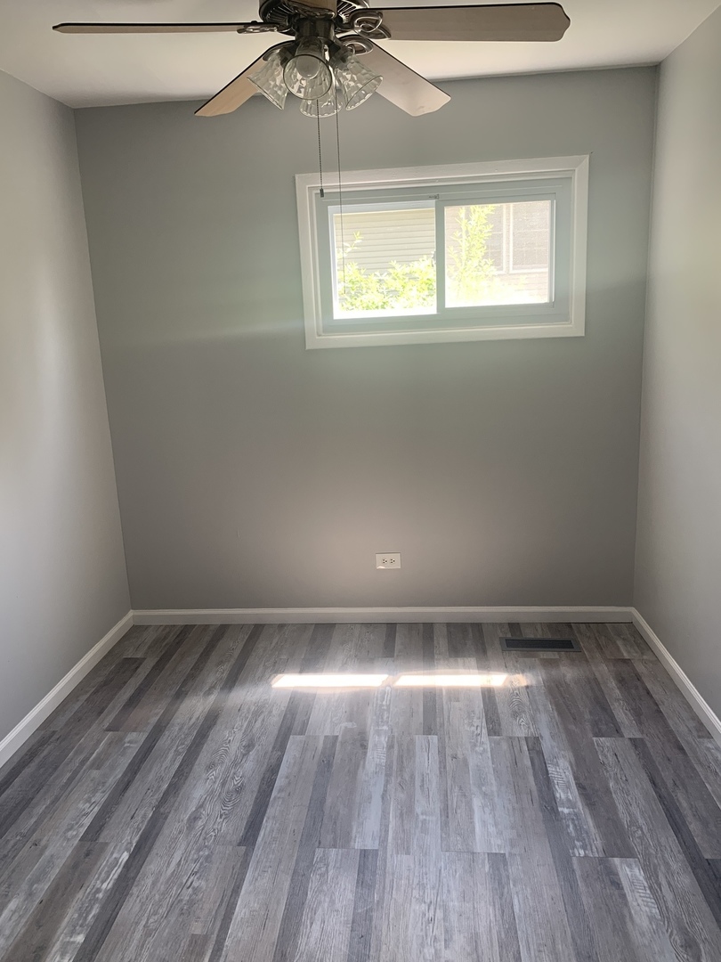 305 Tiverton Lane Steger, IL 60475 - Photo 8 of 13 an empty room with wooden floor chandelier fan and windows