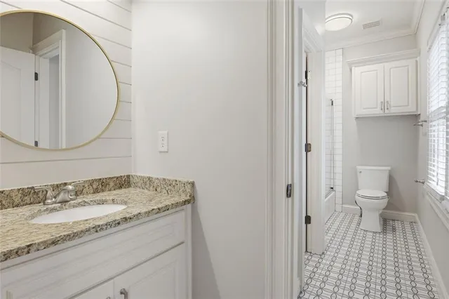 a bathroom with a granite countertop sink a toilet and a mirror