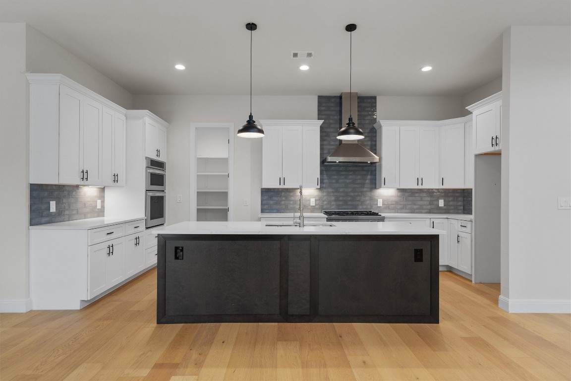 7705 Calcutta Run Drive Jonestown, TX 78645 - Photo 10 of 40 a kitchen with kitchen island granite countertop a stove a sink and white cabinets