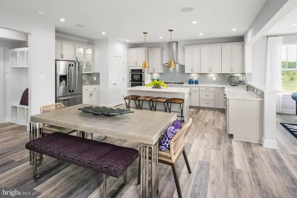 a open kitchen with stainless steel appliances granite countertop a dining table chairs refrigerator sink and microwave