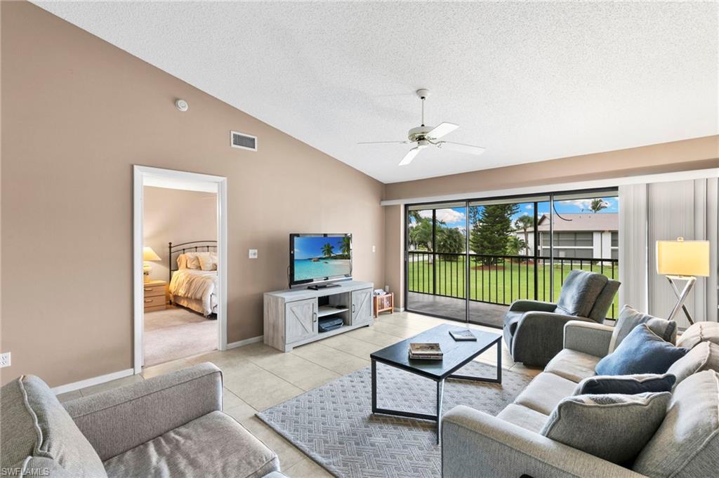 236 Pebble Beach Circle, Unit A202 Naples, FL 34113 - Photo 5 of 25 a living room with furniture and a floor to ceiling window