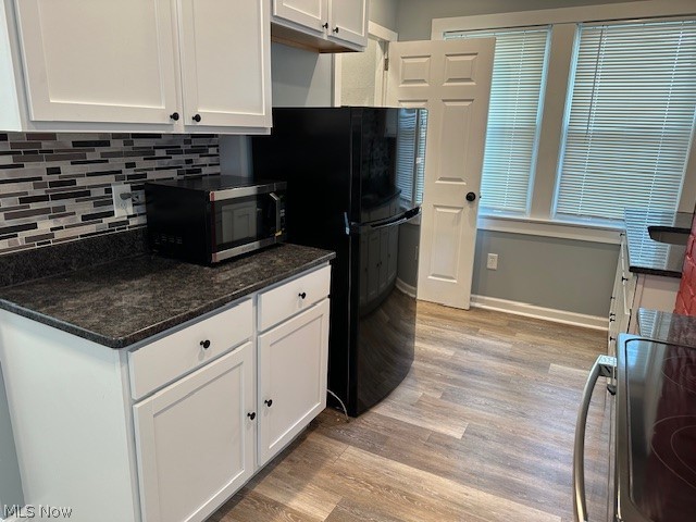 1388 Brookline Road Cleveland, OH 44121 - Photo 12 of 30 Kitchen with white cabinetry, stove, light hardwood / wood-style flooring, dark stone counters, and backsplash