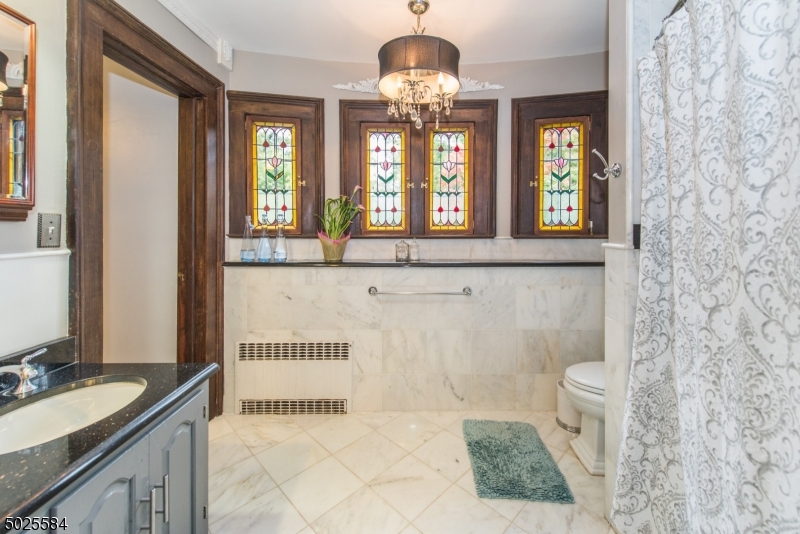 89 Ridgewood Avenue Glen Ridge, NJ 07028 - Photo 15 of 21 a bathroom with a granite countertop sink a large mirror and a bathtub next to a window
