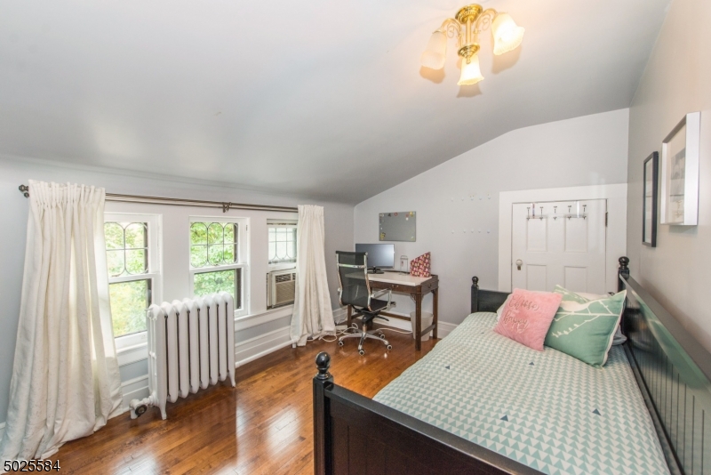 89 Ridgewood Avenue Glen Ridge, NJ 07028 - Photo 18 of 21 a bedroom with a bed and a table in it with wooden floor
