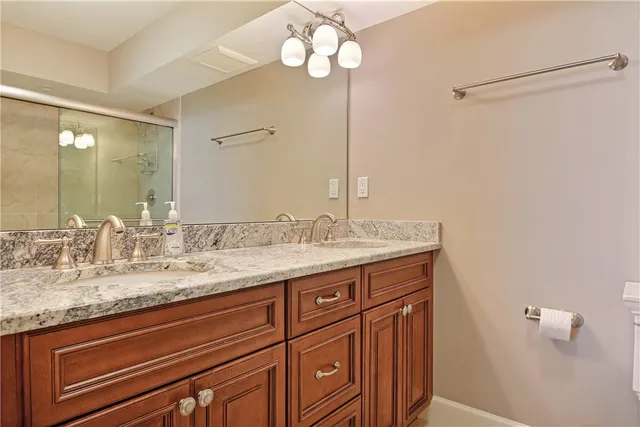 a bathroom with a granite countertop sink a light fixture and a mirror