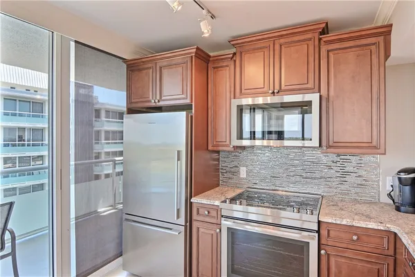 a kitchen with stainless steel appliances granite countertop a refrigerator a stove and a sink with cabinets