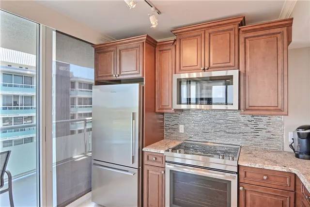 a kitchen with stainless steel appliances granite countertop a refrigerator a stove and a sink with cabinets