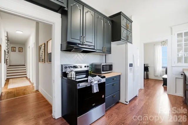 a kitchen with stainless steel appliances a refrigerator a sink and wooden floors