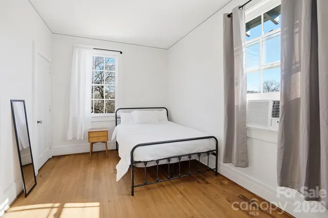 a bedroom with a bed wooden floor and a window