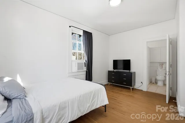 a bedroom with a bed and a flat tv screen on the dresser