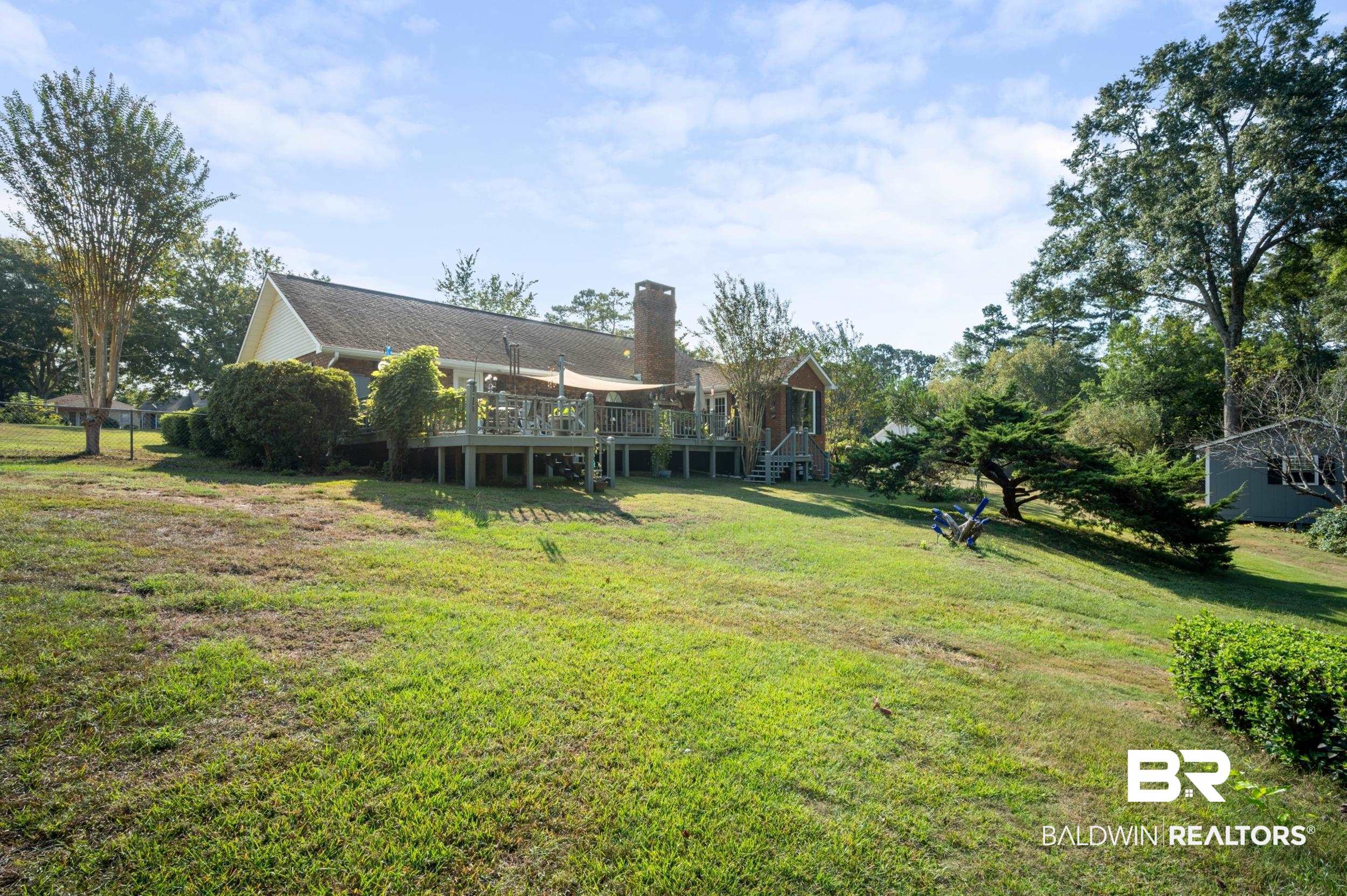 550 Norwood Road Monroeville, AL 36460 - Photo 39 of 46 Rear view of property featuring a wooden deck, a lawn, a chimney, and view of wooded area