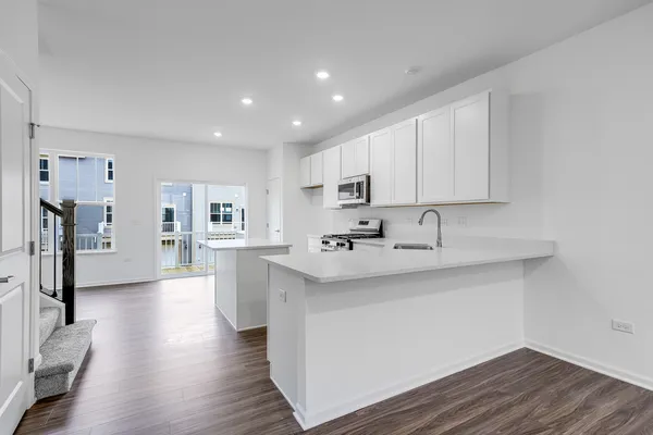 a large white kitchen with wooden floor and a sink