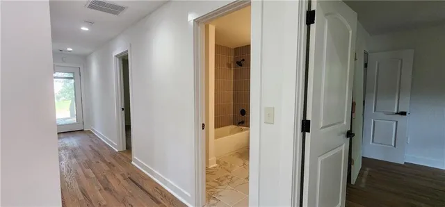 a view of a hallway with wooden floor and closet area