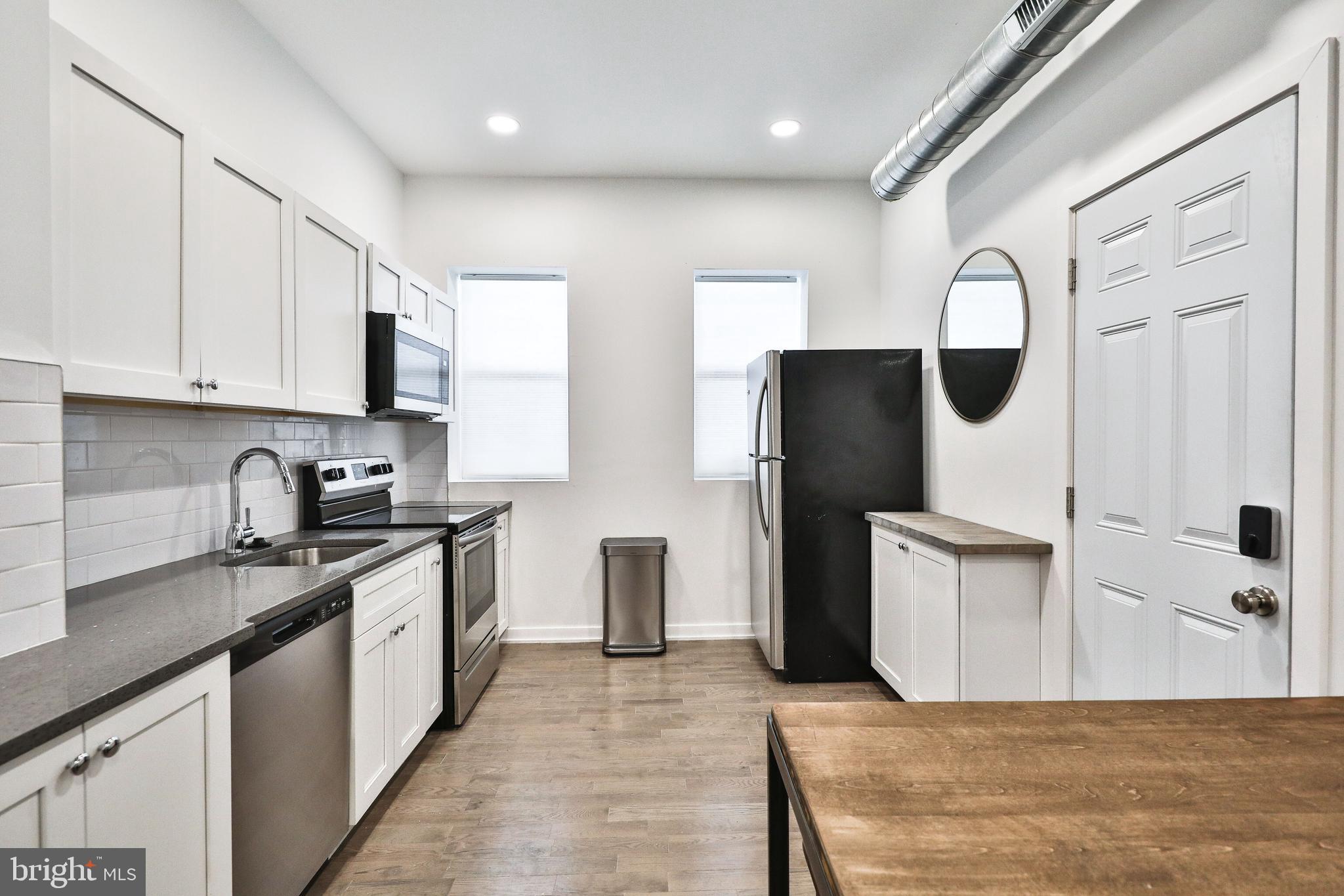 3217 Turner Street Philadelphia, PA 19121 - Photo 6 of 18 a kitchen with stainless steel appliances granite countertop a refrigerator a sink dishwasher and white cabinets with wooden floor