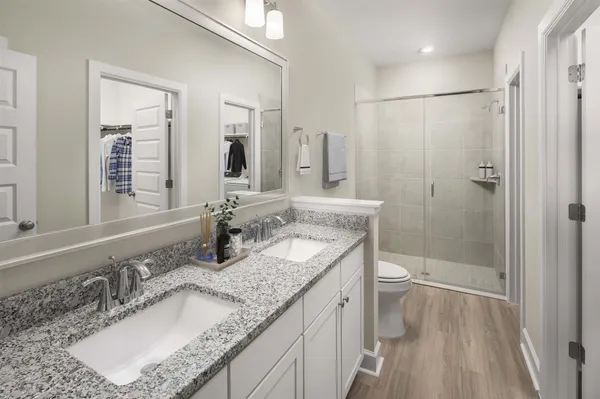 a bathroom with a granite countertop sink a mirror a toilet and shower