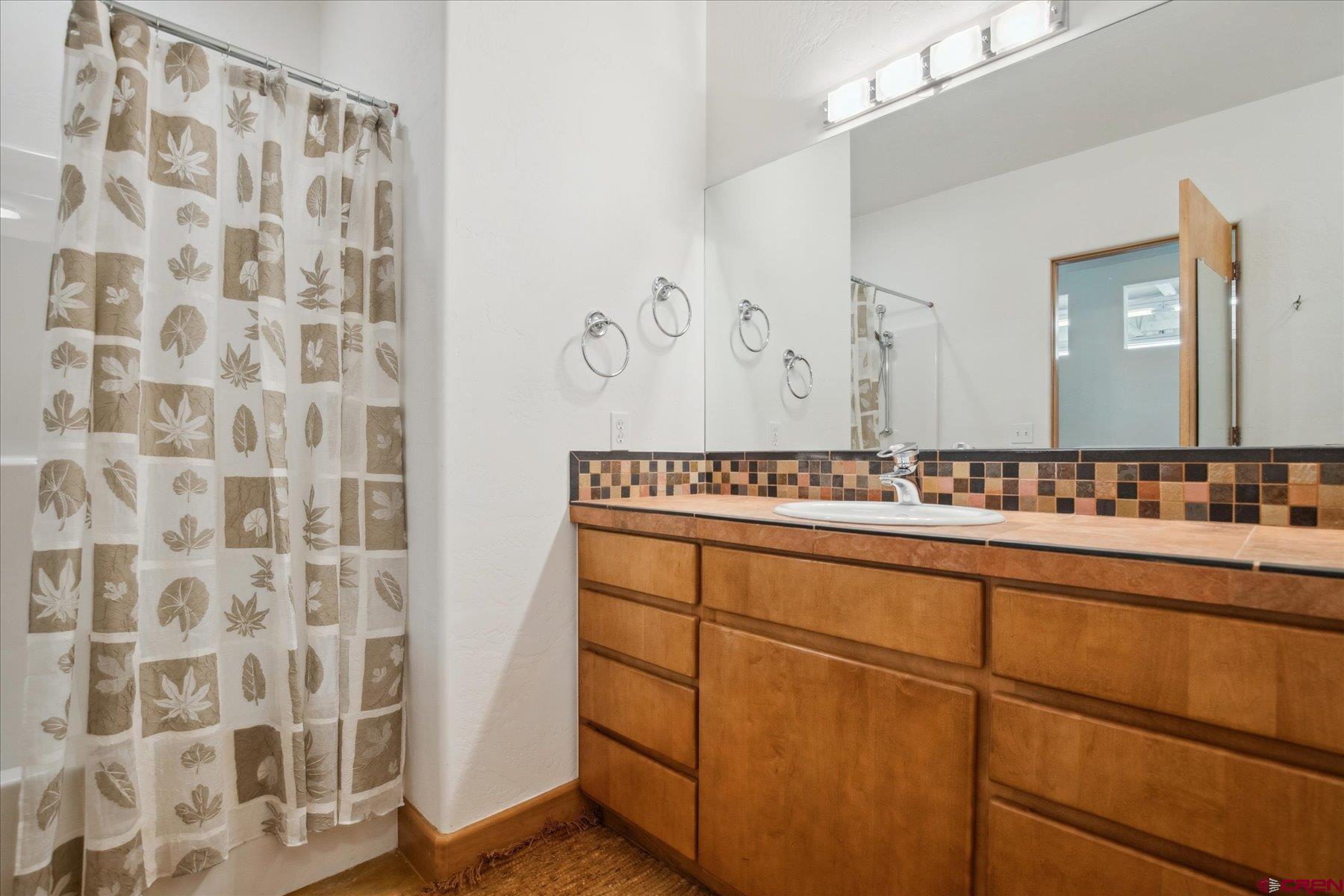 152 Peak Trail Drive Durango, CO 81303 - Photo 34 of 44 a bathroom with a sink a mirror and a shower curtain