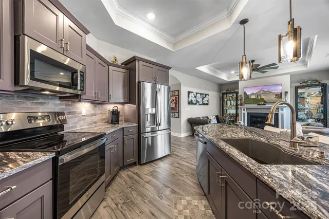 a kitchen with granite countertop a sink stainless steel appliances and cabinets