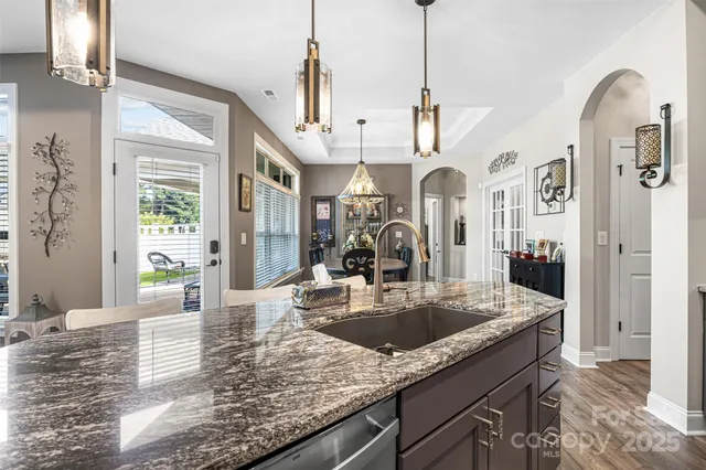 a view of a kitchen with granite countertop a sink stainless steel appliances cabinets and a dining table