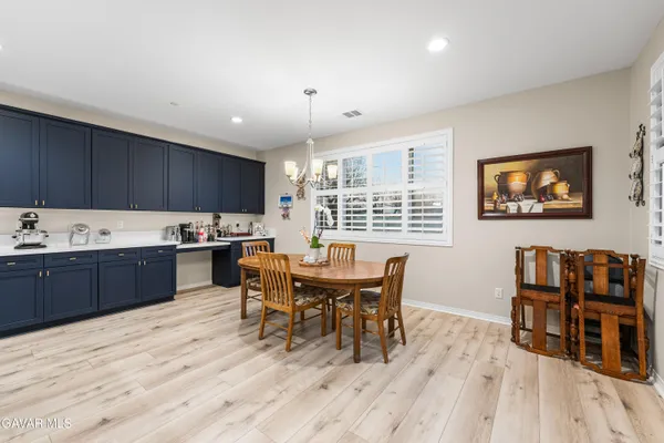 a dining hall with stainless steel appliances kitchen island a table chairs and wooden floor