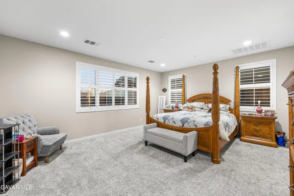 a bed sitting in a spacious bedroom next to a window and dresser