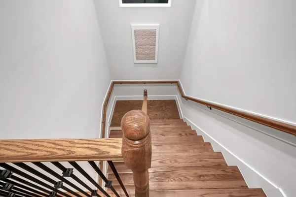 a view of staircase with lots of frames on wall and wooden floor