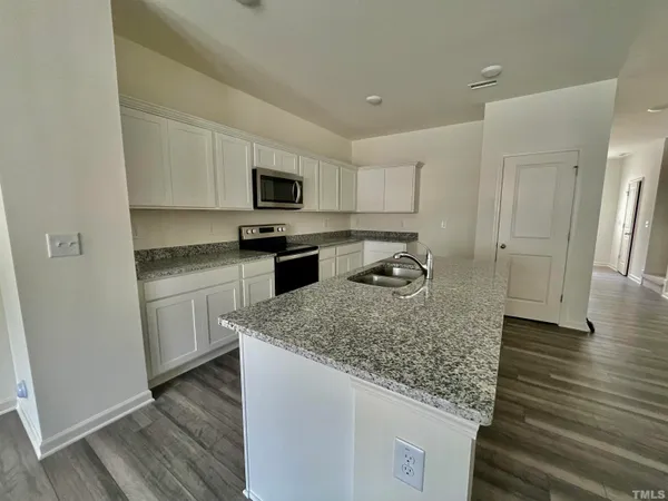 a kitchen with granite countertop a sink dishwasher stove and microwave with wooden floor