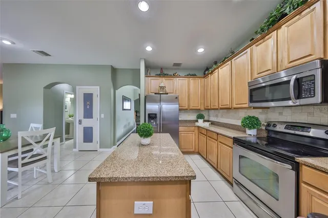 a kitchen with kitchen island granite countertop a sink a counter top stainless steel appliances and cabinets
