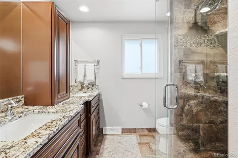 a bathroom with a granite countertop shower a sink and a mirror