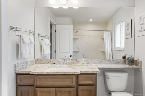 a bathroom with a granite countertop sink a toilet and a mirror