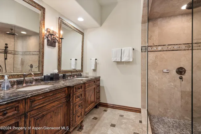 a bathroom with a double vanity sink mirror and shower