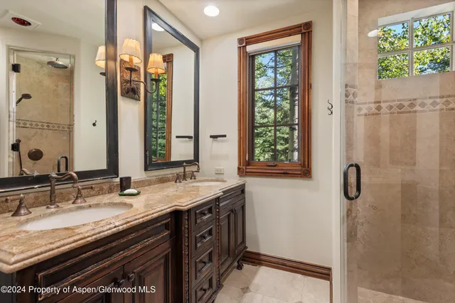 a bathroom with a granite countertop sink a mirror a vanity and a shower
