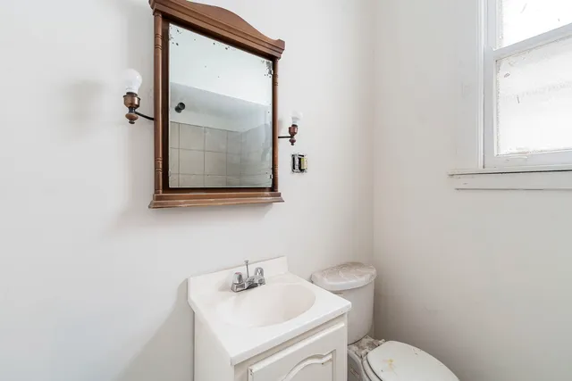 a bathroom with a toilet sink vanity and mirror