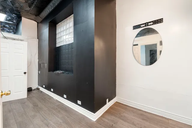 an empty room with wooden floor mirror and windows