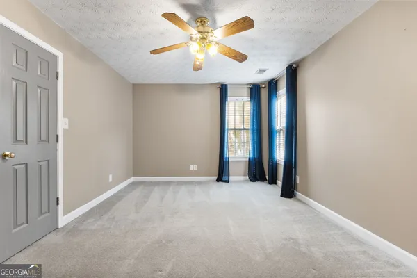 a view of an empty room and chandelier fan