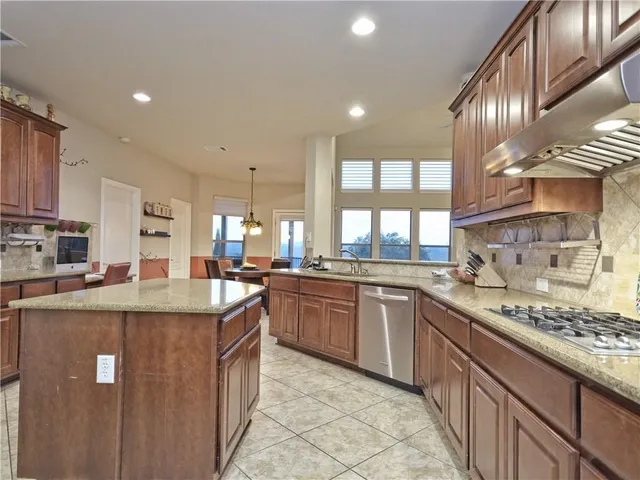 a kitchen with stainless steel appliances granite countertop a stove top oven a sink a refrigerator and a granite counter tops