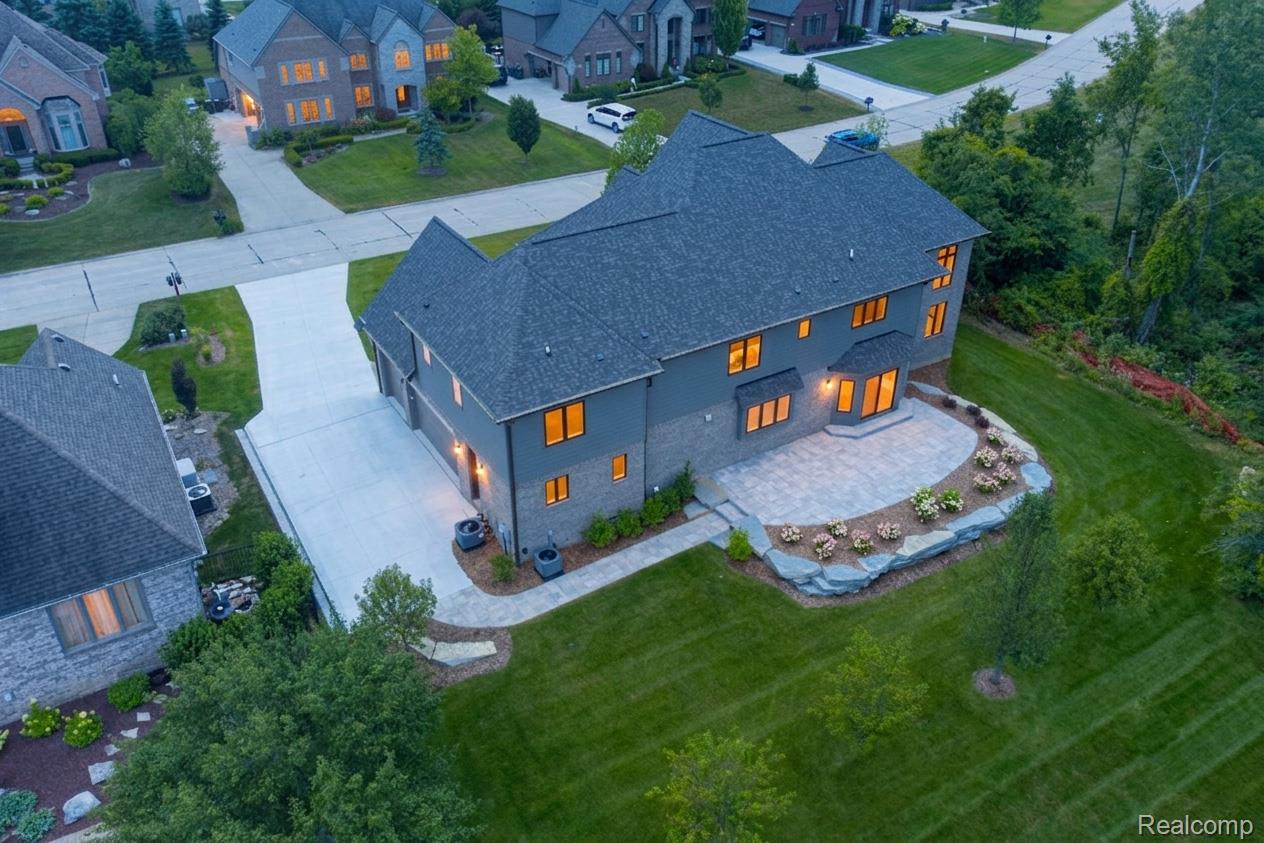 3836 Coachwood Lane Rochester, MI 48309 - Photo 5 of 82 Rear exterior featuring a stone paver patio, stone retaining wall, and landscaped planting beds