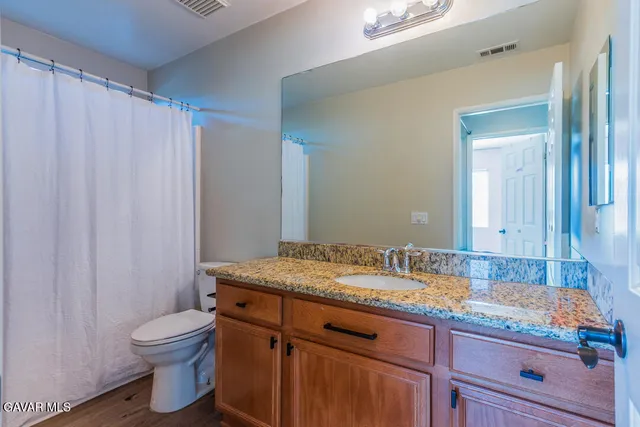 a bathroom with a granite countertop sink toilet and mirror