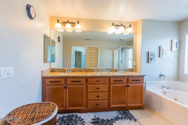 a spacious bathroom with a granite countertop sink a mirror a and a bathtub