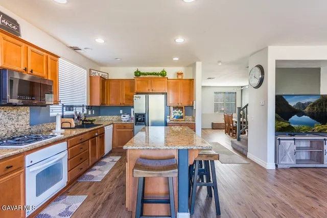 a large kitchen with cabinets wooden floor white stainless steel appliances and dining table