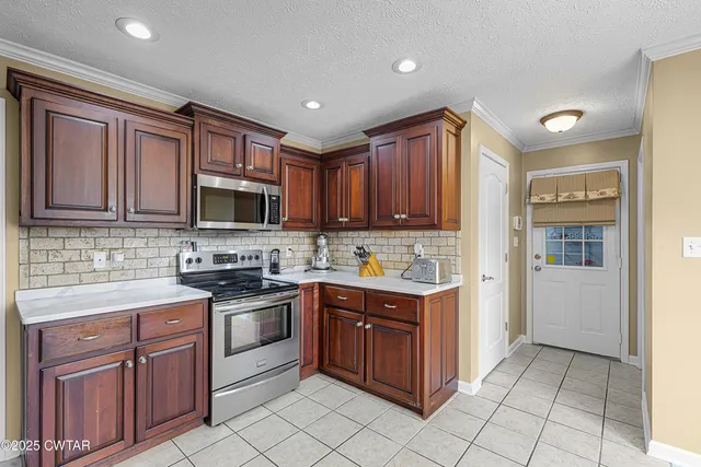 a kitchen with stainless steel appliances granite countertop a stove top oven a sink dishwasher and a refrigerator with wooden cabinets