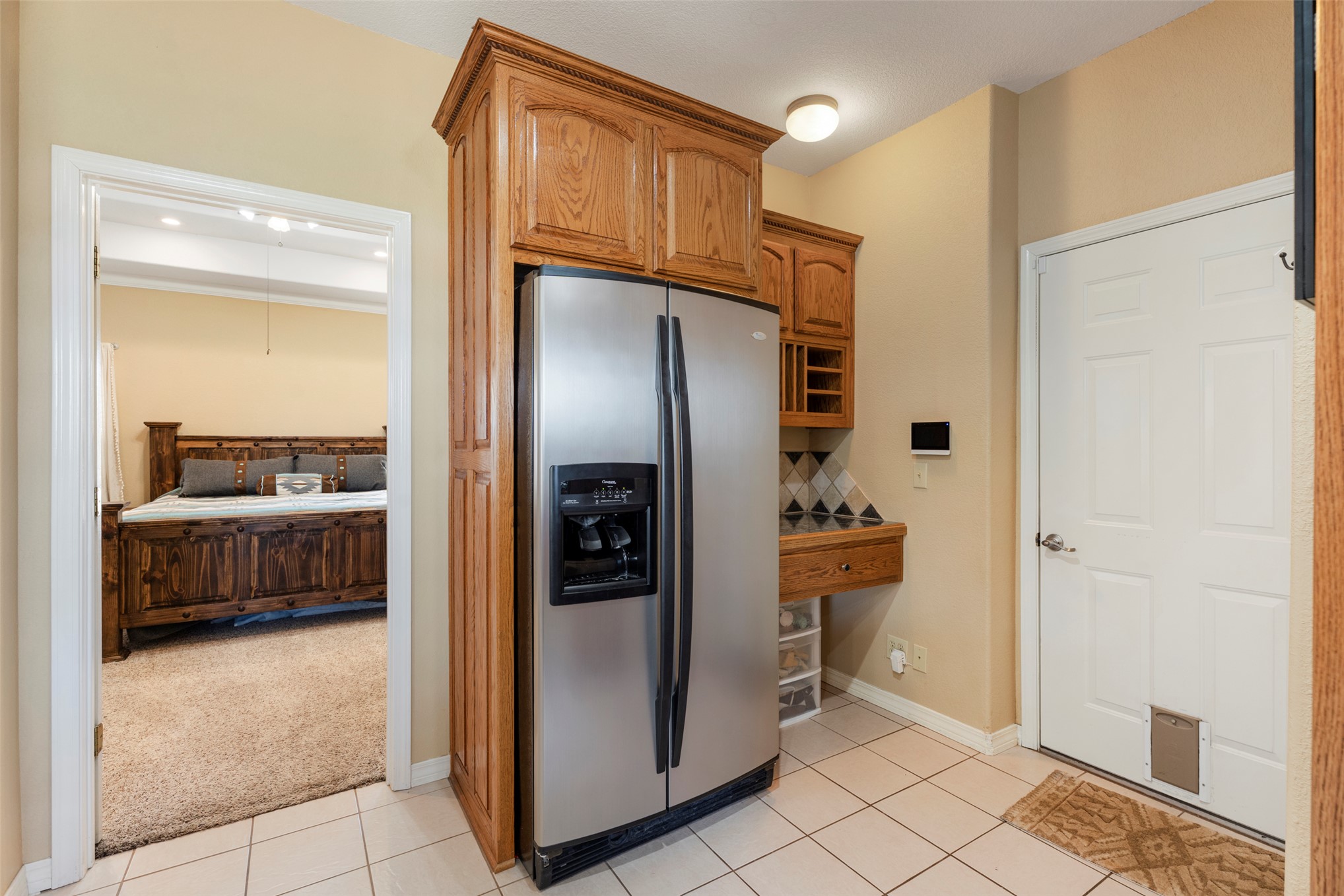 20233 East 570 Road Colcord, OK 74338 - Photo 16 of 39 Stainless steel side-by-side refrigerator, built-in wooden cabinetry, tile flooring, and a paneled white door